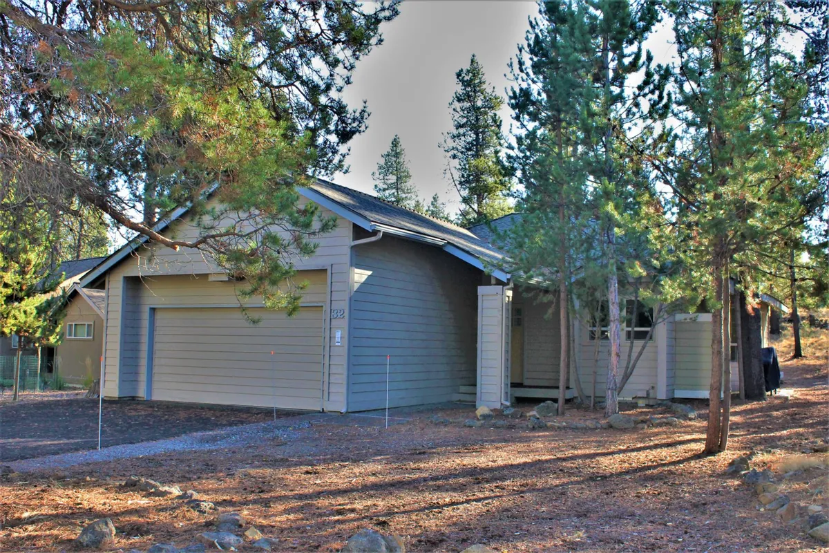 A peaceful exterior shot of the home, nestled among tall trees with a driveway leading up to the house. This scene suggests a tranquil home base where families can return after enjoying activities like swimming, tennis, and sledding.