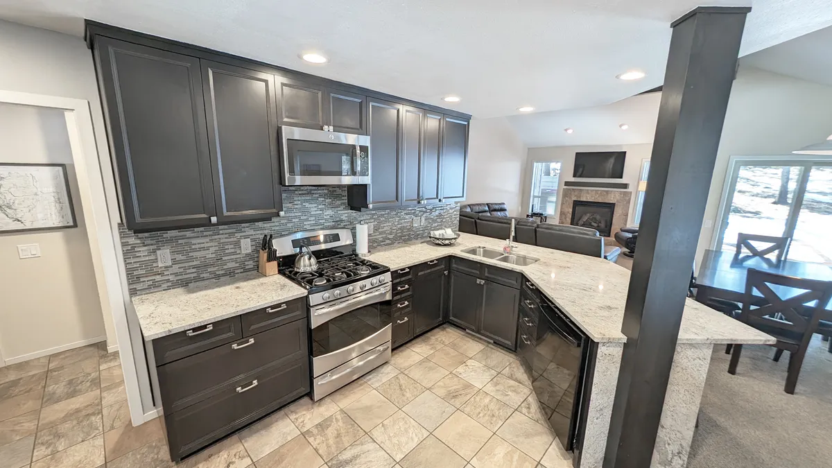 A welcoming, open-concept space encompassing the modern kitchen with stainless steel appliances, granite countertops, and a cozy adjacent seating area. The layout encourages communal cooking and gathering, with family and friends sharing recipes and enjoying lively conversations.